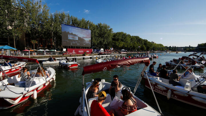People arrive to watch the film "Le Grand Bain" from boats at the Cinema on the water (Cinema sur l'eau) at a floating cinema with 38 socially distant boats at Paris Plages, Paris, France, July 18, 2020.